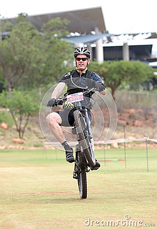 Happy middle aged man popping wheelie at the finish line at Mountain Bike Race Editorial Stock Photo